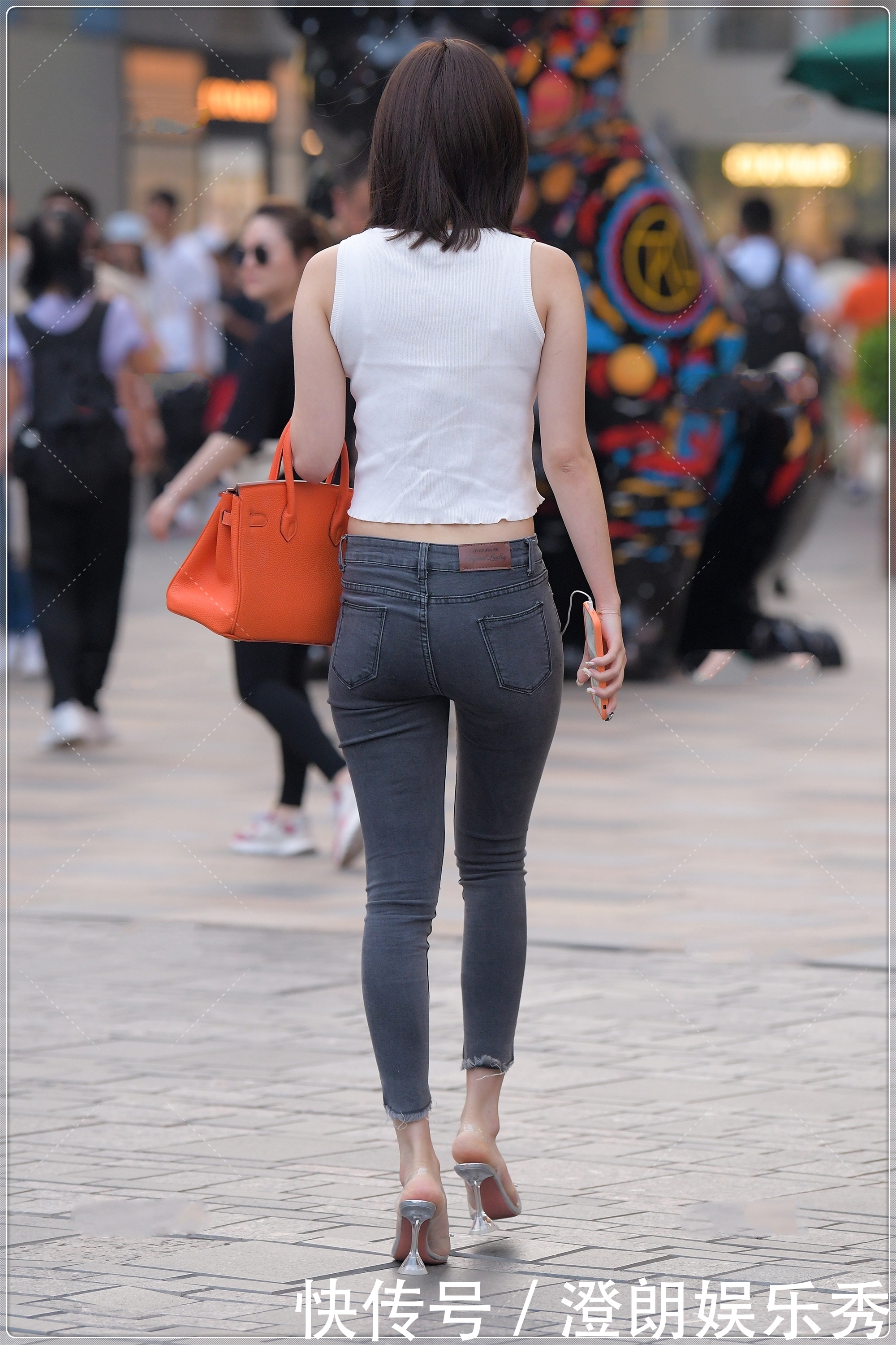 街拍美女简单的白色背心,搭配露膝牛仔裤很时髦,简约时尚