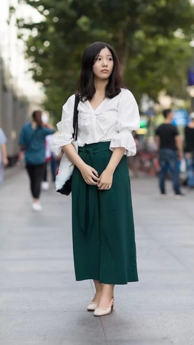 街拍：小姐姐身穿白色的背心搭配上一条半裙，优雅的展示出美丽的双腿
