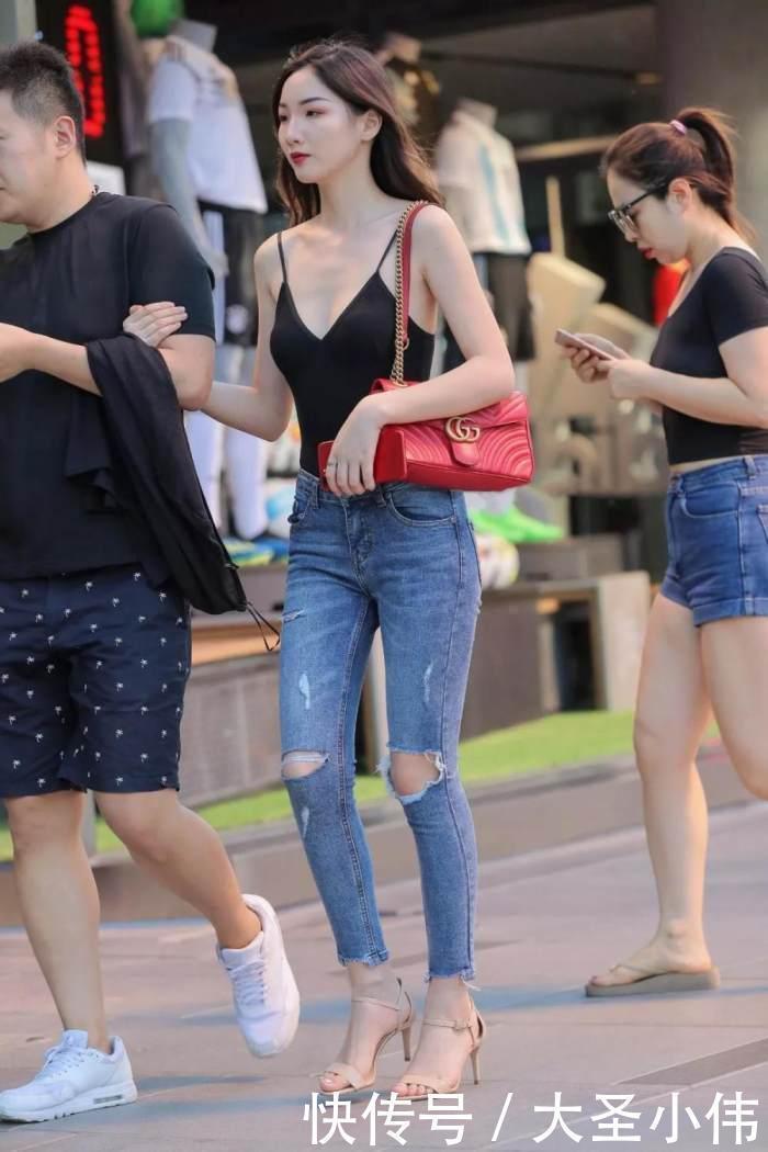 美女街拍小姐姐黑色的吊带抹胸背心搭配浅色的牛仔长裤,性感丰满身材尽显