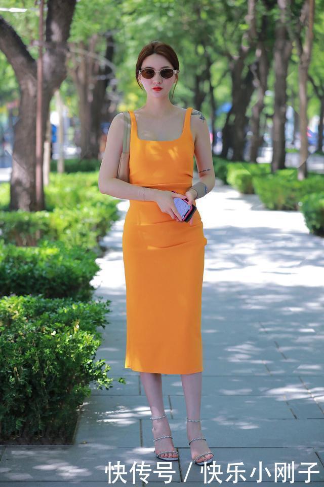 亮眼的橘黄色吊带裙，吊带裙的腰部微微收紧，将皮肤衬得白皙诱人