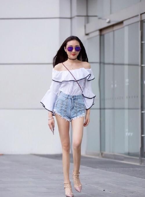 身穿|街拍小姐姐身穿喇叭一字肩上衣搭配浅蓝色牛仔热裤,美丽动人