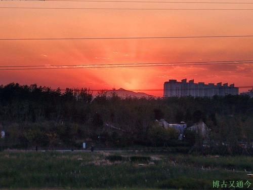 温榆河示范区西园观日落，红光映照远端海淀最高峰
