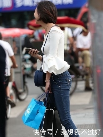 笑容|街拍:紧身牛仔裤搭配白色露肩装的美女,甜美笑容让人印象深刻