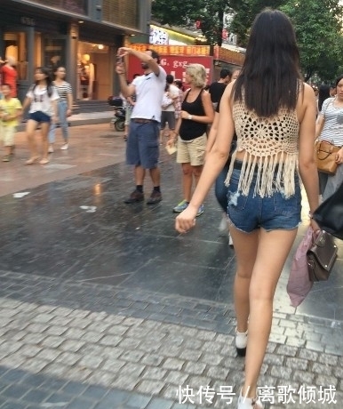 镂空|街拍:美女蓝色紧身高腰牛仔裤搭镂空线衣,给人时尚清凉的感觉