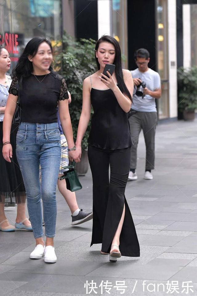 小姐姐黑色喇叭裤搭配了一件吊带衫,展现出了几分随性慵懒的格调