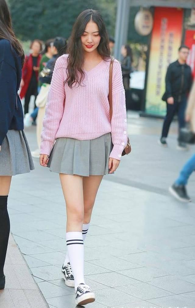 路人街拍，小姐姐选择粉色v领毛衣搭配浅灰色百褶裙，可爱又性感
