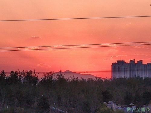 温榆河示范区西园观日落，红光映照远端海淀最高峰