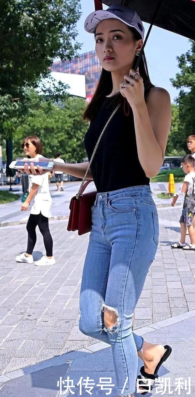 小姐姐穿简约的牛仔裤，配上白色吊带，青春时尚气息十足