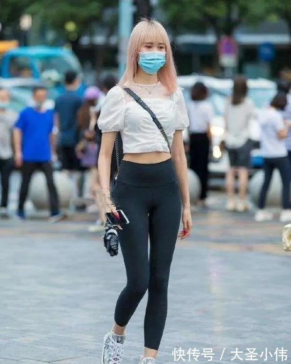 露脐短袖 美女街拍:白色露脐短袖搭配黑色打底裤,可爱显瘦,年轻女孩的必备穿搭