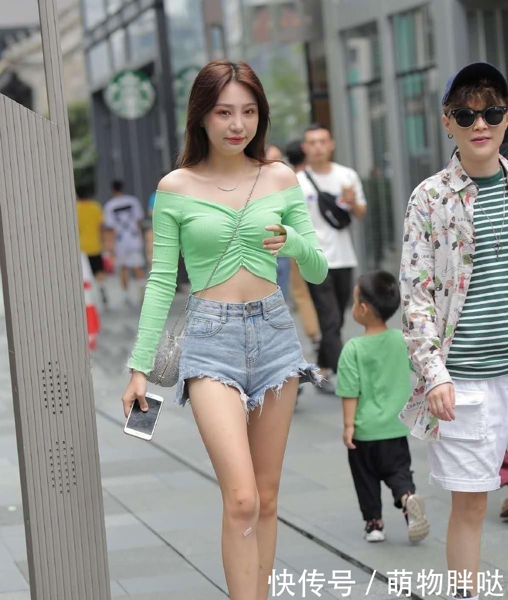 街拍活泼动人的小姐姐，身穿浅绿色一字肩短衫，非常的清新减龄