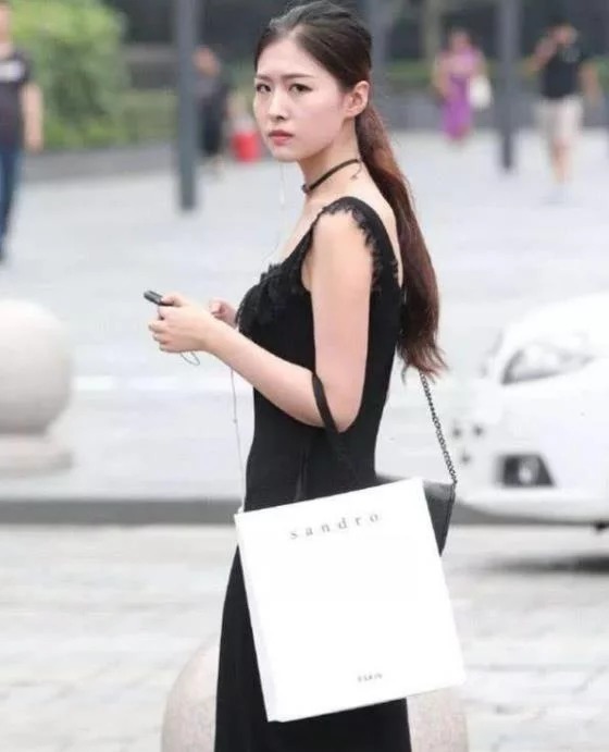 街拍皮肤白皙的美女,身穿黑色连衣裙,女人味十足