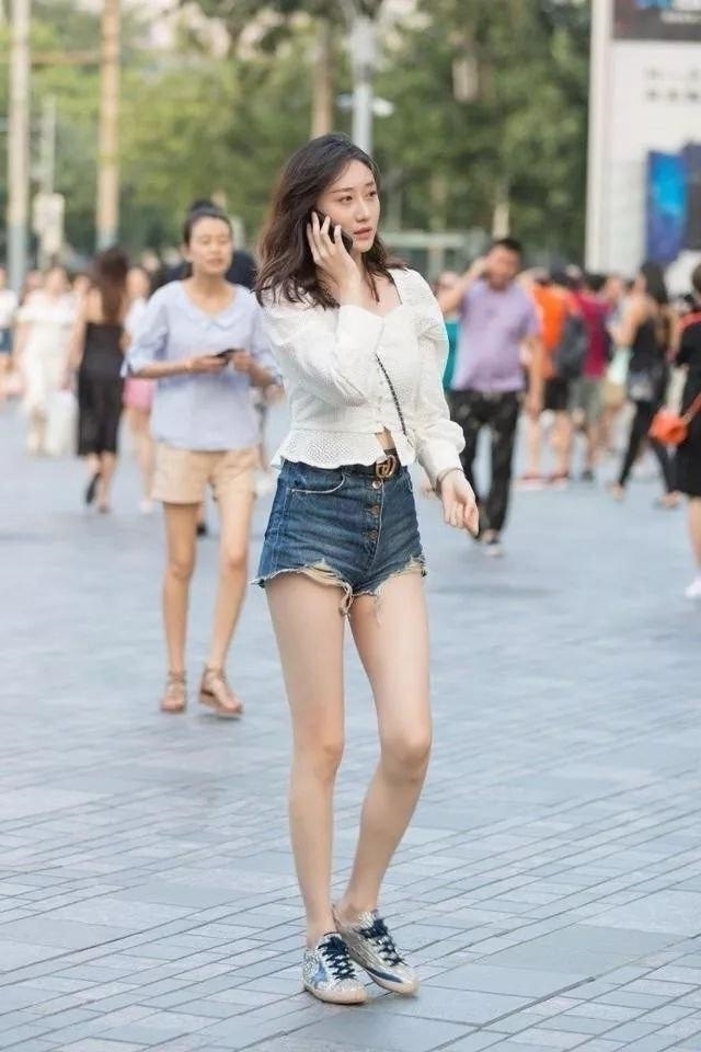 牛仔热裤|路人街拍,靓女白色上衣搭配牛仔热裤,整个人看起来高挑迷人