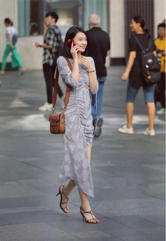 街拍打电话的小姐姐,身穿浅灰色的时尚连衣裙,面带微笑气质不错