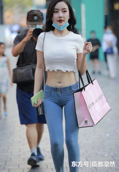 美女白色上衣肚脐装搭配浅蓝色牛仔裤,增加了穿搭的创意和时尚感