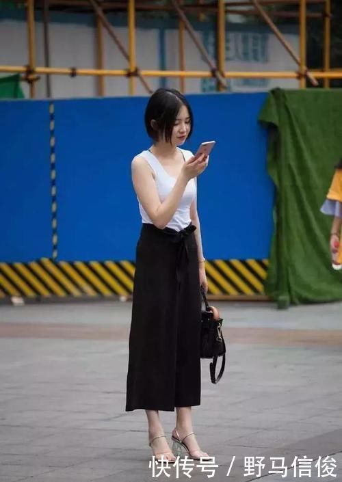 街拍小姐姐半袖上衣搭配黑色的短款下装,非常时尚具有美感