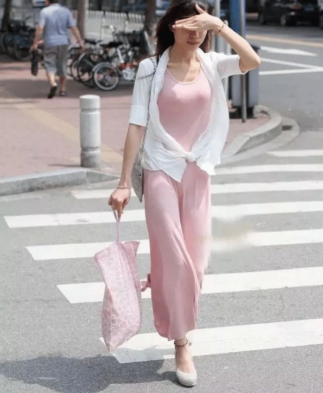 街拍紧身的粉色吊带连衣裙,搭配时尚白色防晒衣,优雅而性感