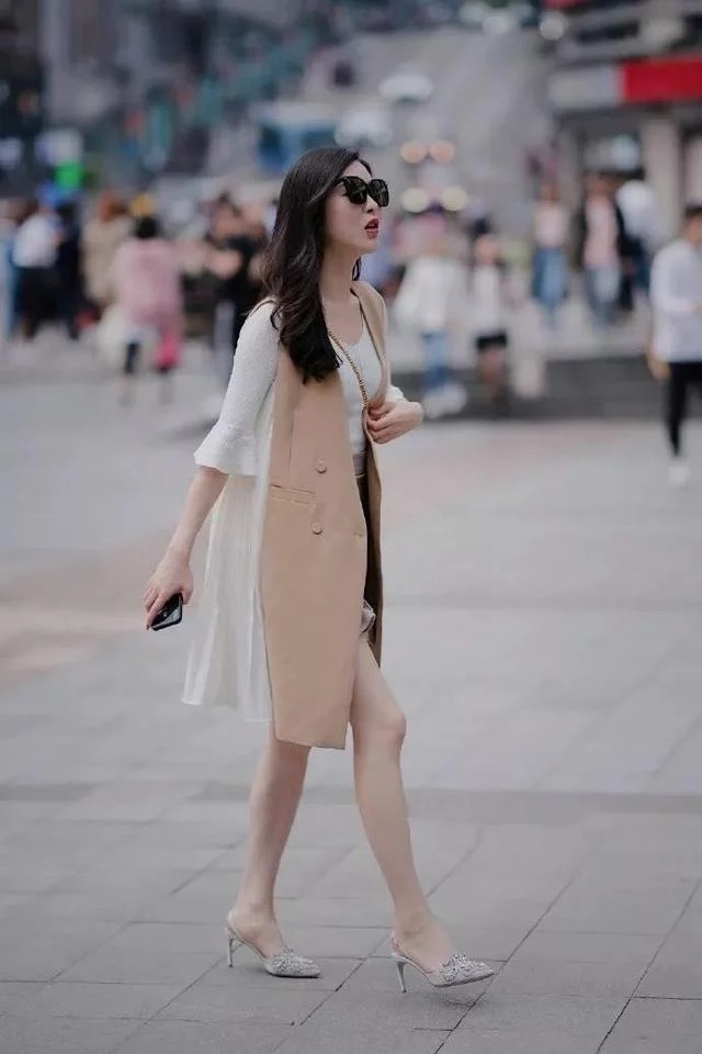 街拍:小姐姐身穿白色的背心搭配上一条半裙,优雅的展示出美丽的双腿