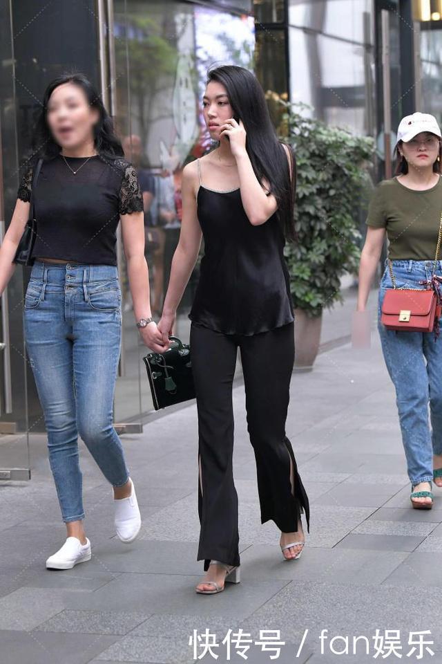 小姐姐黑色喇叭裤搭配了一件吊带衫,展现出了几分随性慵懒的格调