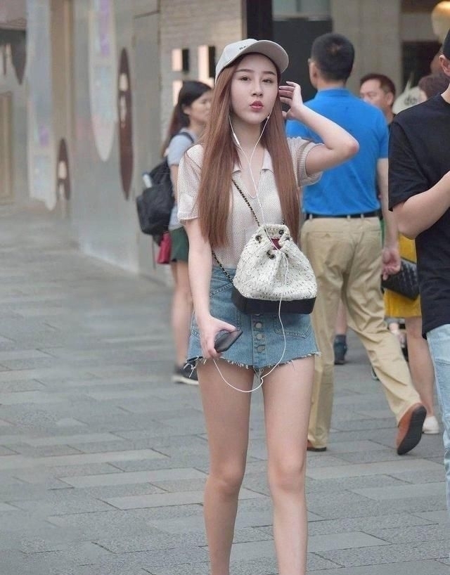 街拍小姐姐白色的长袖T恤搭配蓝色牛仔热裤,时髦靓丽