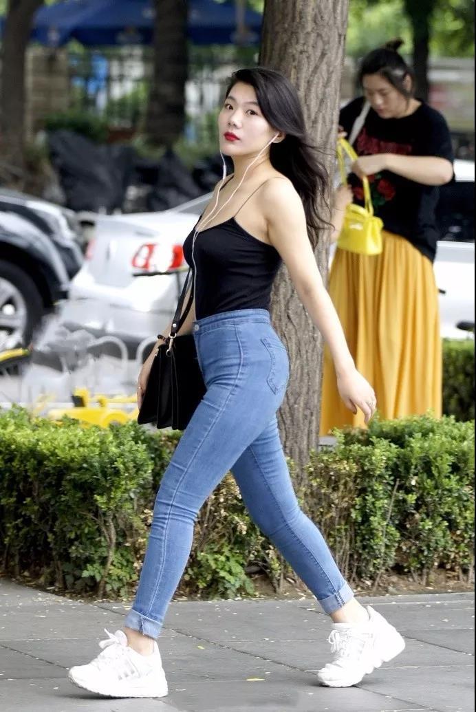 吊带|街拍黑色吊带背心搭紧身牛仔裤的性感姑娘,大方洒脱的气质