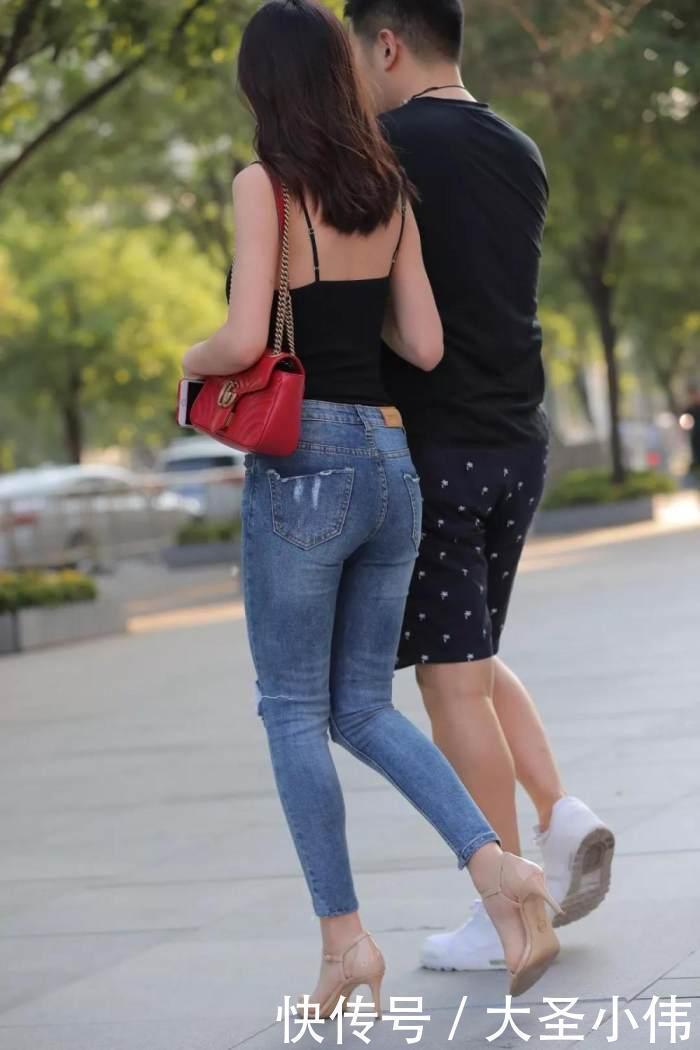 美女街拍小姐姐黑色的吊带抹胸背心搭配浅色的牛仔长裤,性感丰满身材尽显