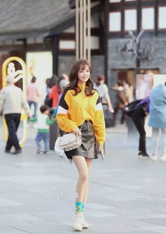 街拍:美女身穿黄色毛衣搭配小皮裙,笑容甜美可爱,非常时髦