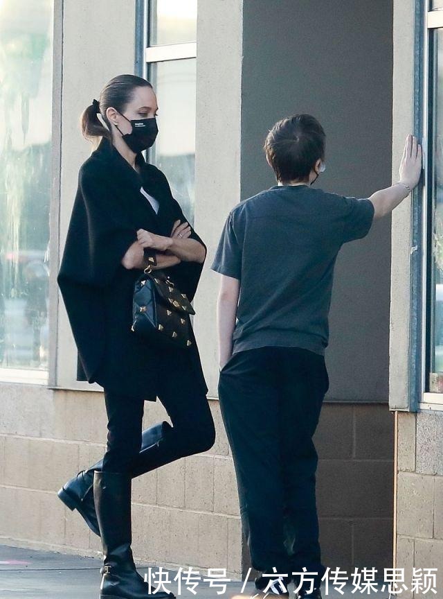 安吉丽娜·朱莉穿黑色斗篷上衣搭配细腿裤,和儿子逛街,真潇洒