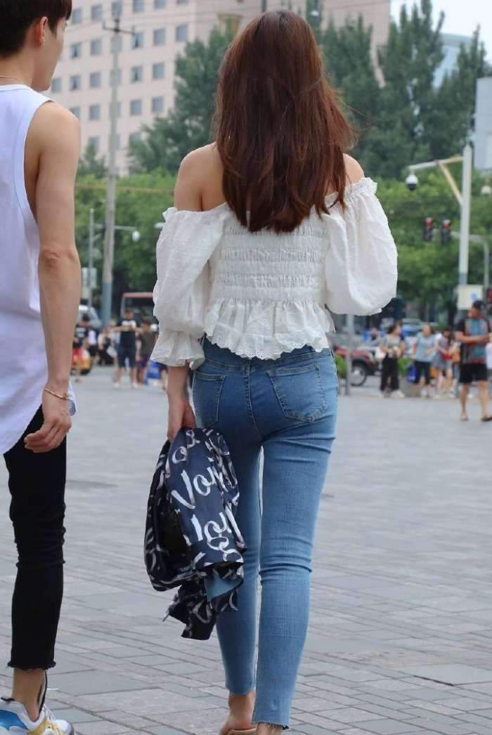穿着白色|街拍:美女穿着白色的抹胸上衣搭配牛仔裤,美腿曲线完美的展现!