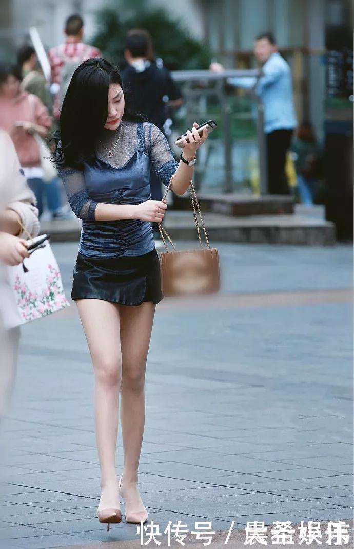 美女街拍美女个子非常高，乌黑靓丽的秀发散落在肩上，妩媚感十足