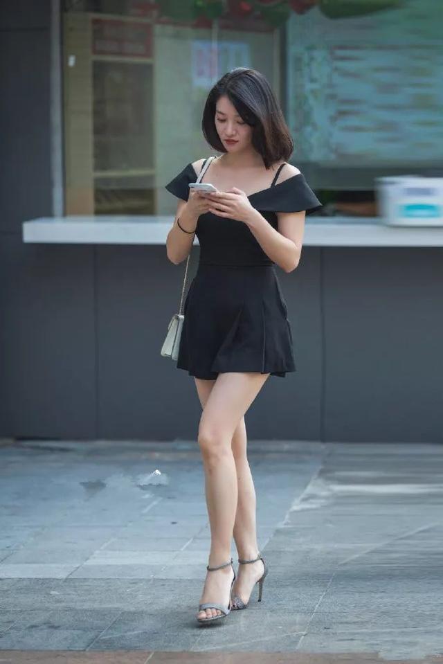 背心|街拍:专注手机的美女,背心配黑色碎花裙,凸显完美身材