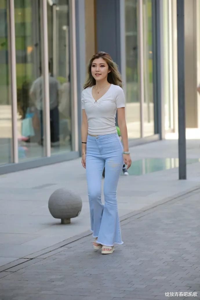 白色V领修身T恤，加上喇叭牛仔裤，尽显出休闲时尚的风格