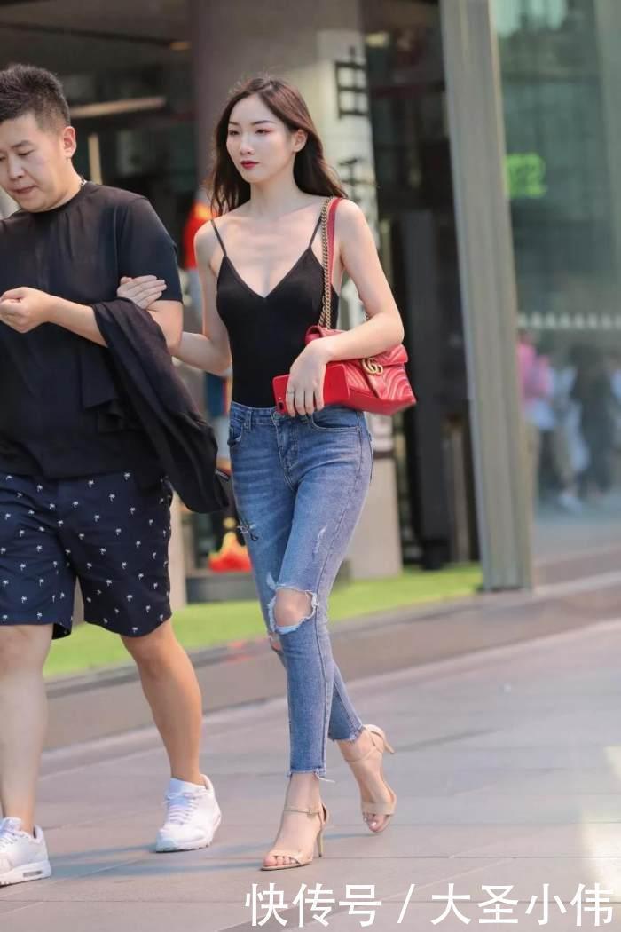 美女街拍小姐姐黑色的吊带抹胸背心搭配浅色的牛仔长裤,性感丰满身材尽显
