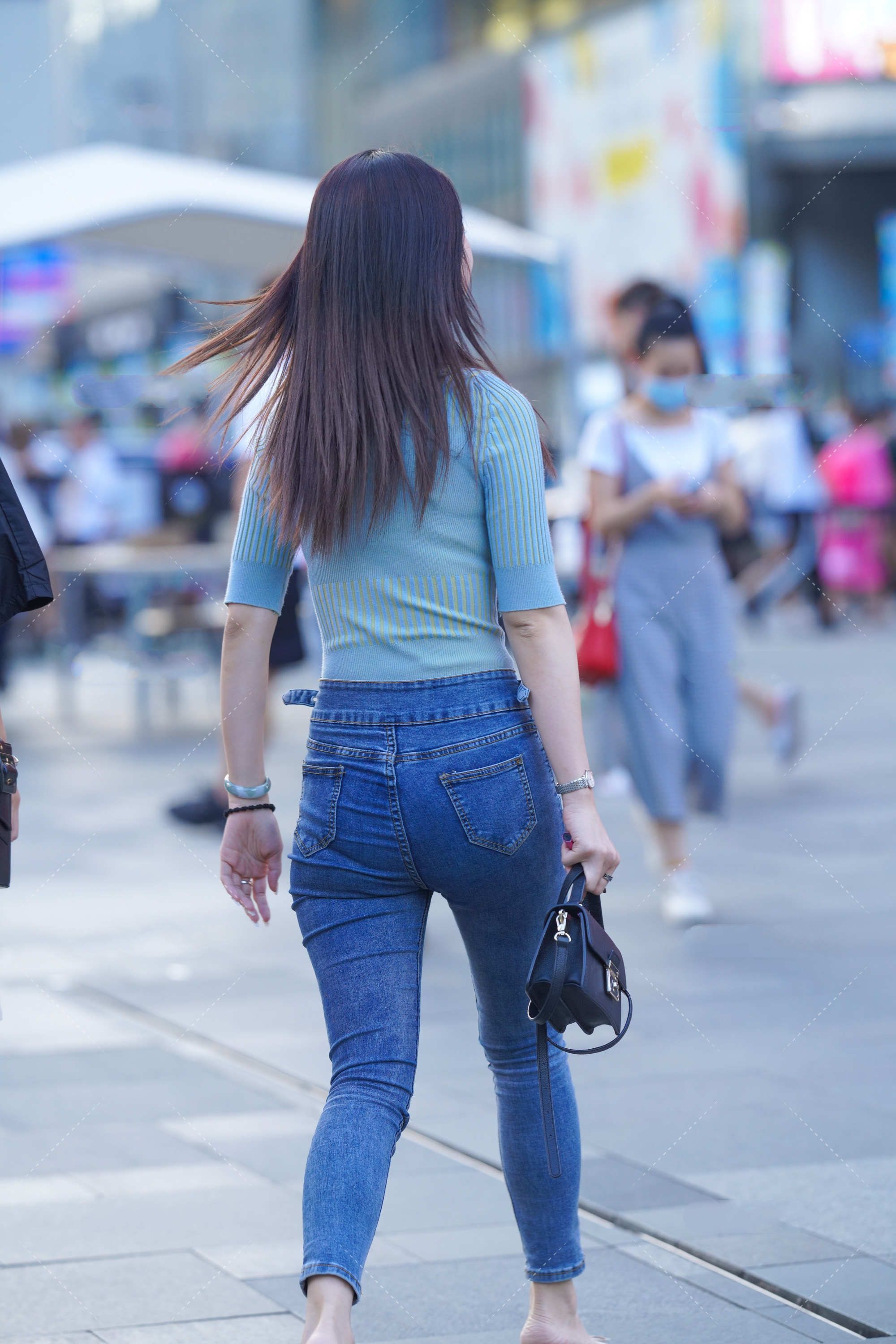 蓝绿色修身上衣搭配深色牛仔裤，手拿黑色手提包，清爽简约的搭配