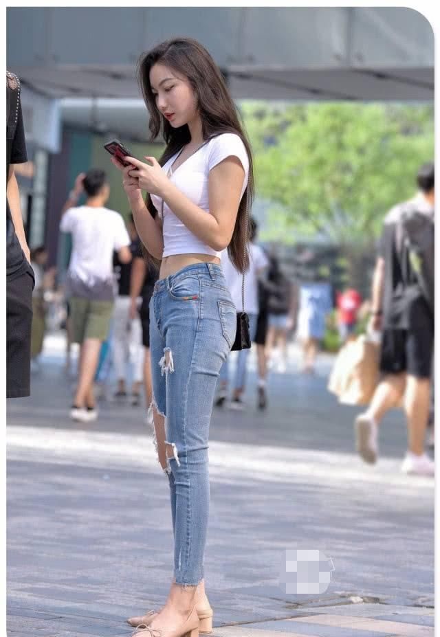 街拍美女紧身牛仔裤小姐姐帮人捡起掉落物品，心地善良的女神