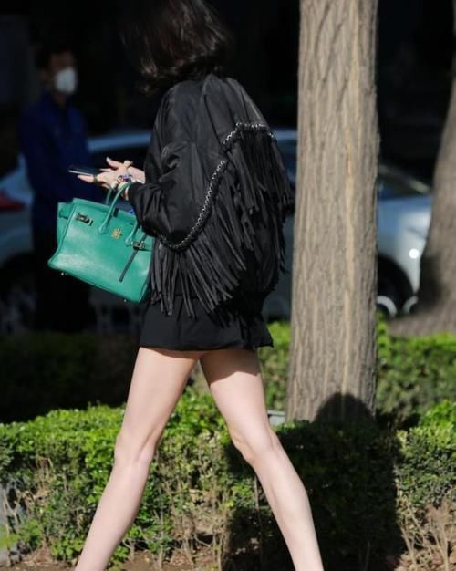 街拍小姐姐身穿一件白色短袖紧身T恤,搭配一条黑色牛仔短裤