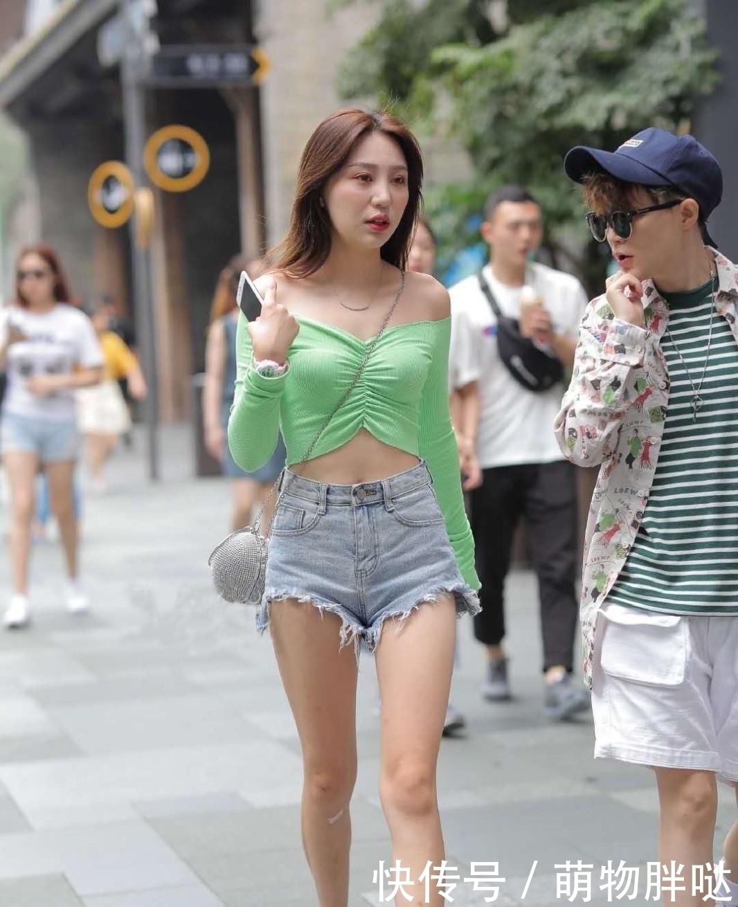 街拍活泼动人的小姐姐，身穿浅绿色一字肩短衫，非常的清新减龄