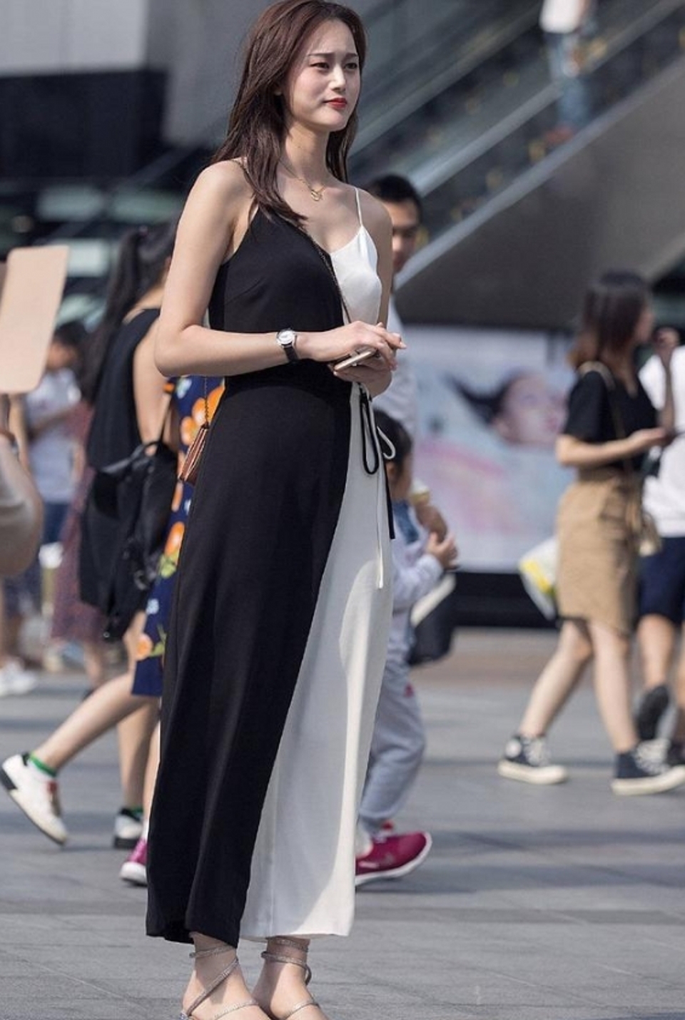路人街拍，美女选择了一款拼色设计的吊带长裙，彰显了她的魅力