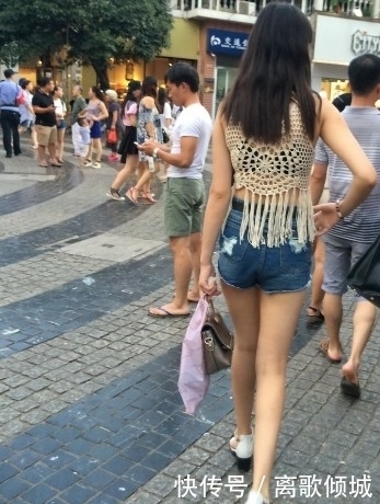 镂空|街拍:美女蓝色紧身高腰牛仔裤搭镂空线衣,给人时尚清凉的感觉