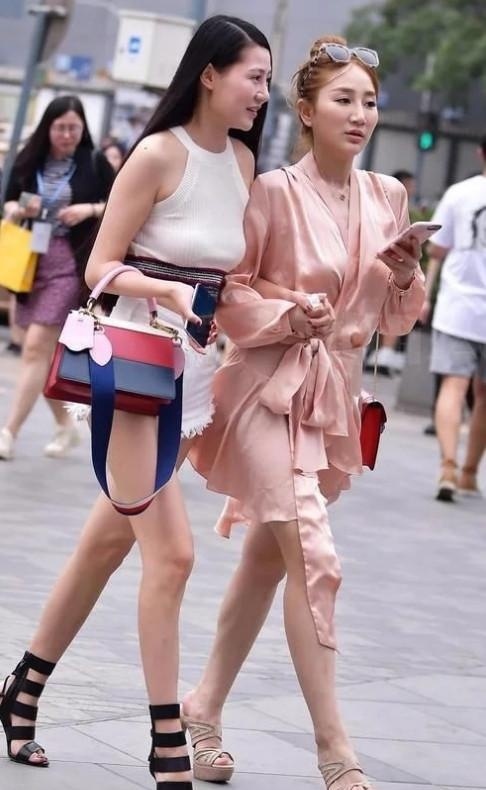 身穿|街拍:两个漂亮的小姐姐一起逛街,一个身穿短裤,一个像裹了睡衣