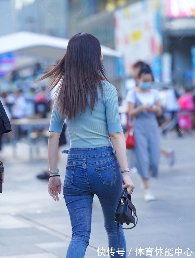 蓝绿色修身上衣搭配深色牛仔裤,手拿黑色