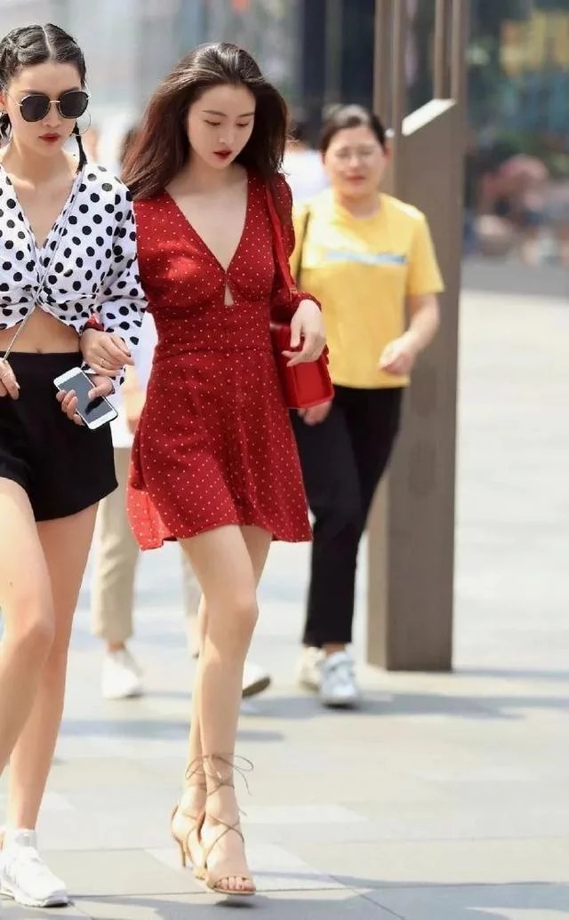 街拍:小姐姐身穿白色的背心搭配上一条半裙,优雅的展示出美丽的双腿