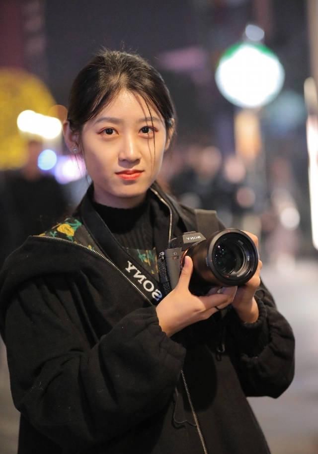 路人街拍，姑娘身穿黑色的短裤，露出修长的双腿很是俏皮