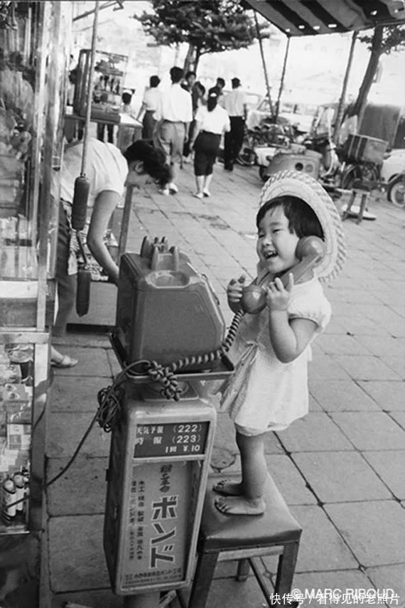 公用电话前的日本小朋友，个子不高，站在凳子上打电话。