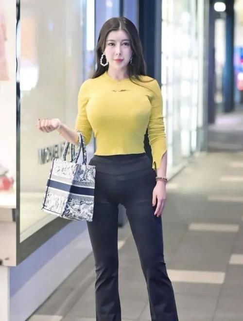 修身 色彩艳丽的黄色挂颈上衣,配黑色修身打底裤,身材高挑,气质优雅