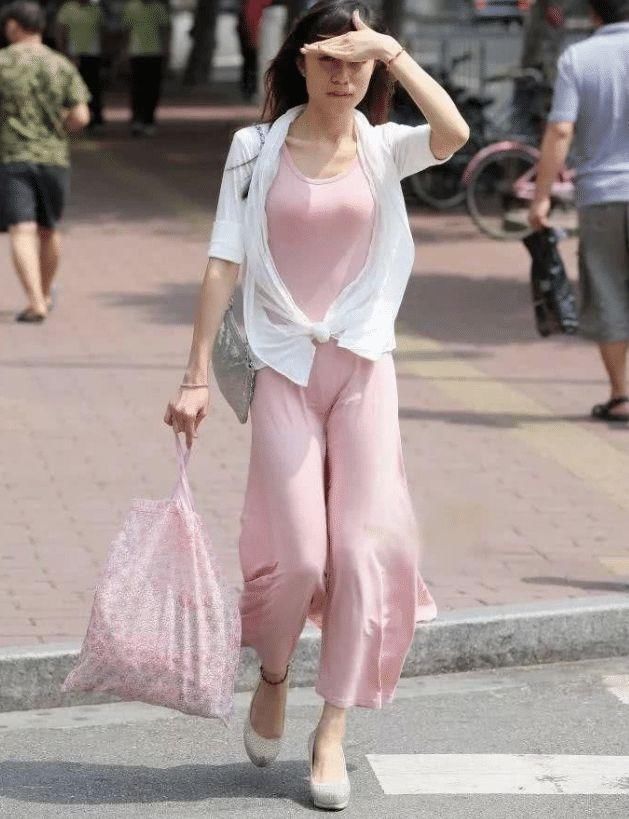 街拍紧身的粉色吊带连衣裙,搭配时尚白色防晒衣,优雅而性感