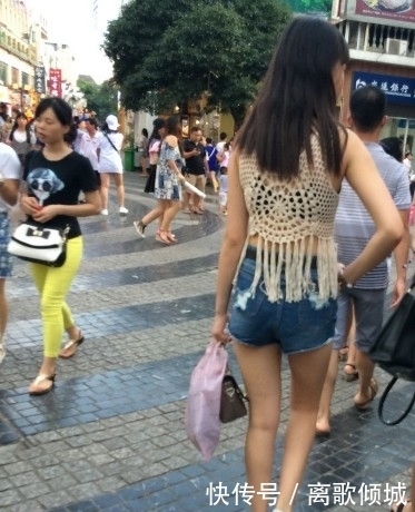 镂空|街拍:美女蓝色紧身高腰牛仔裤搭镂空线衣,给人时尚清凉的感觉