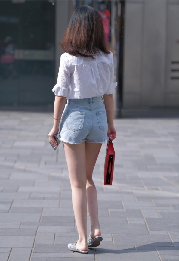 牛仔短裤 戴墨镜的美女肤白貌美,白色衬衫搭配牛仔短裤,大长腿实力抢镜