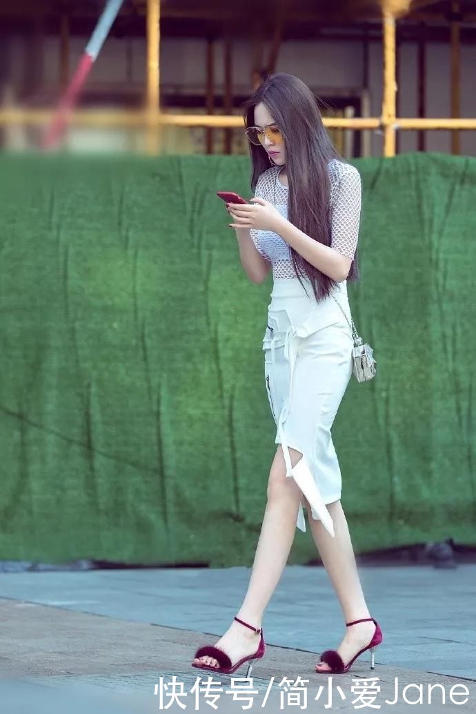 美女脚上踩着一双红色高跟凉鞋，带有绒毛的设计看上去温柔又时尚