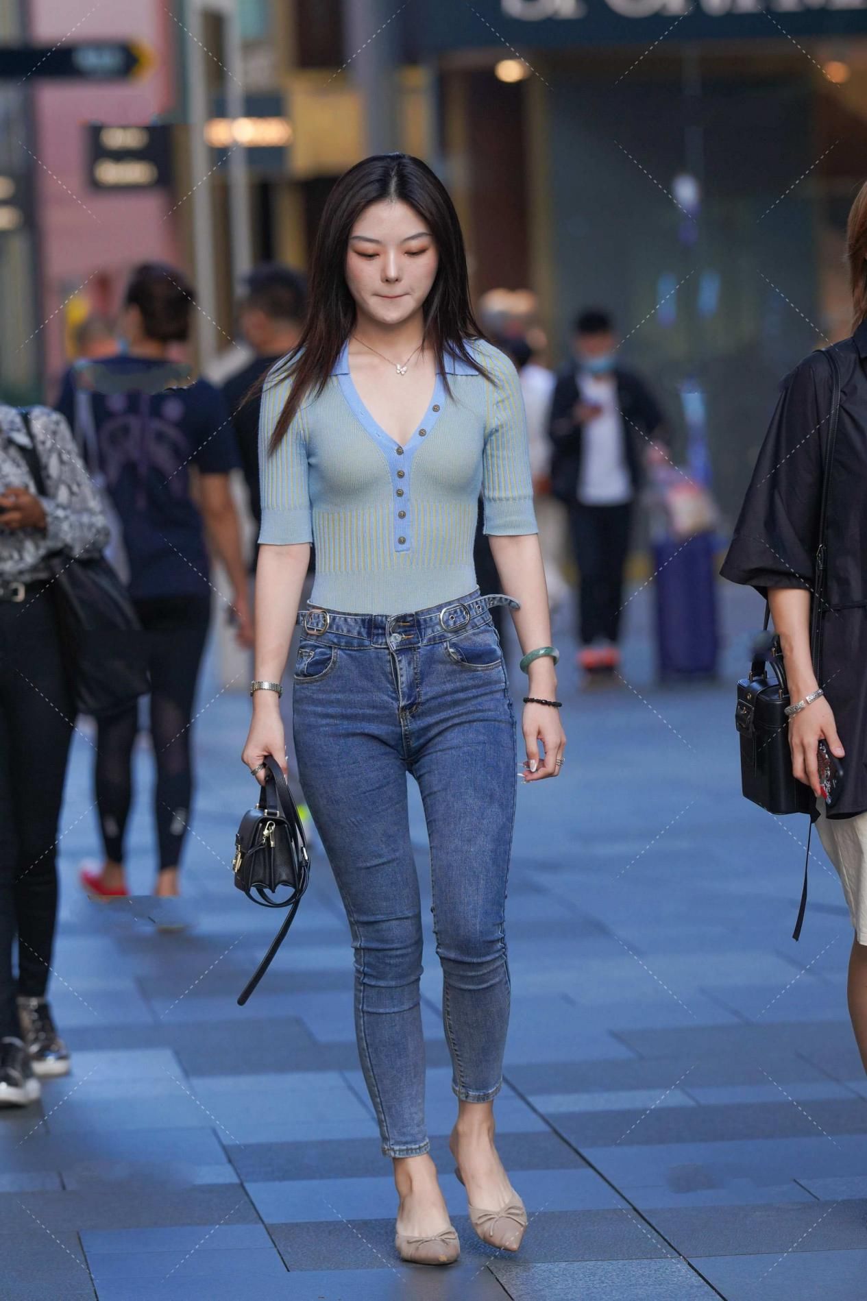 蓝绿色修身上衣搭配深色牛仔裤，手拿黑色手提包，清爽简约的搭配