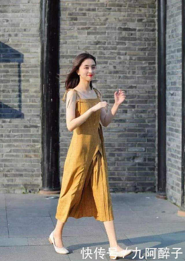 路人街拍靓女穿着一件浅黄色的连衣裙,显得非常妩媚